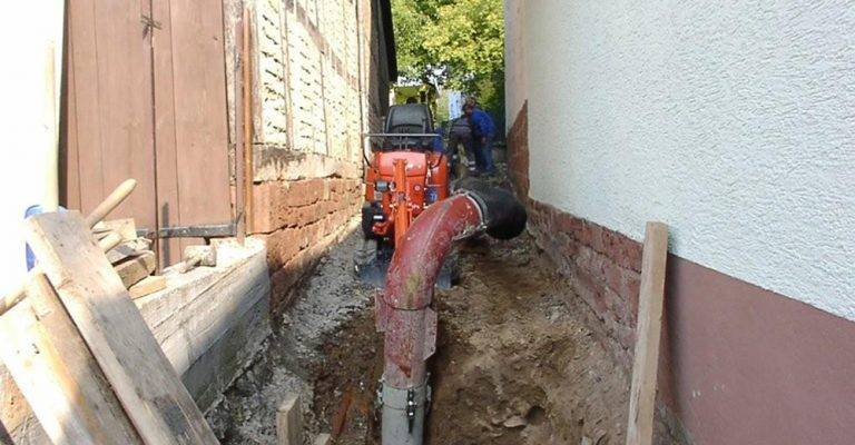 Terrassement entre deux bâtiments avec mini-pelle connectée à l’aspiratrice